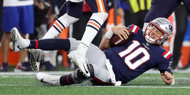 Mac Jones #10 of the New England Patriots slides down after running with the ball during the first half against the Chicago Bears at Gillette Stadium on October 24, 2022 in Foxborough, Massachusetts.