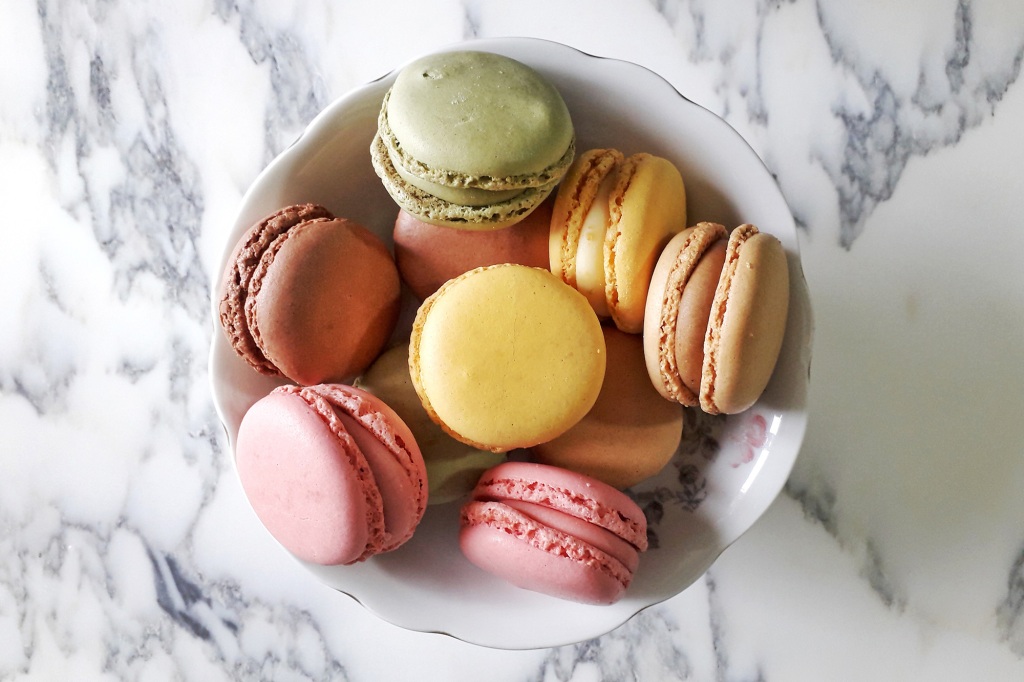 Colorful Macaroons on marble background seen from above.