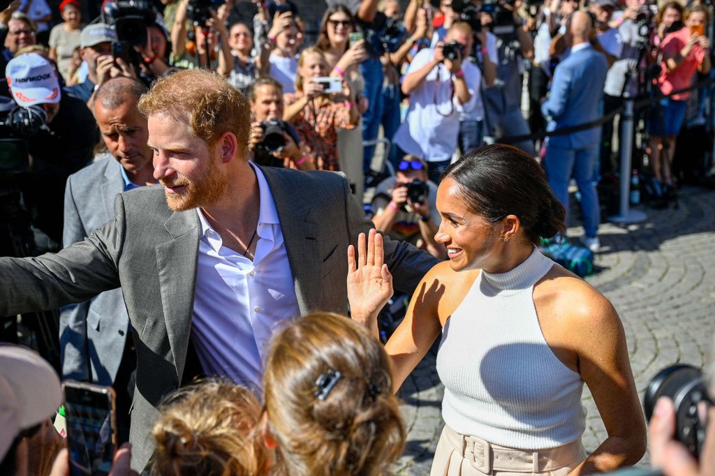 Meghan Markle with Prince Harry greeting a crowd. 