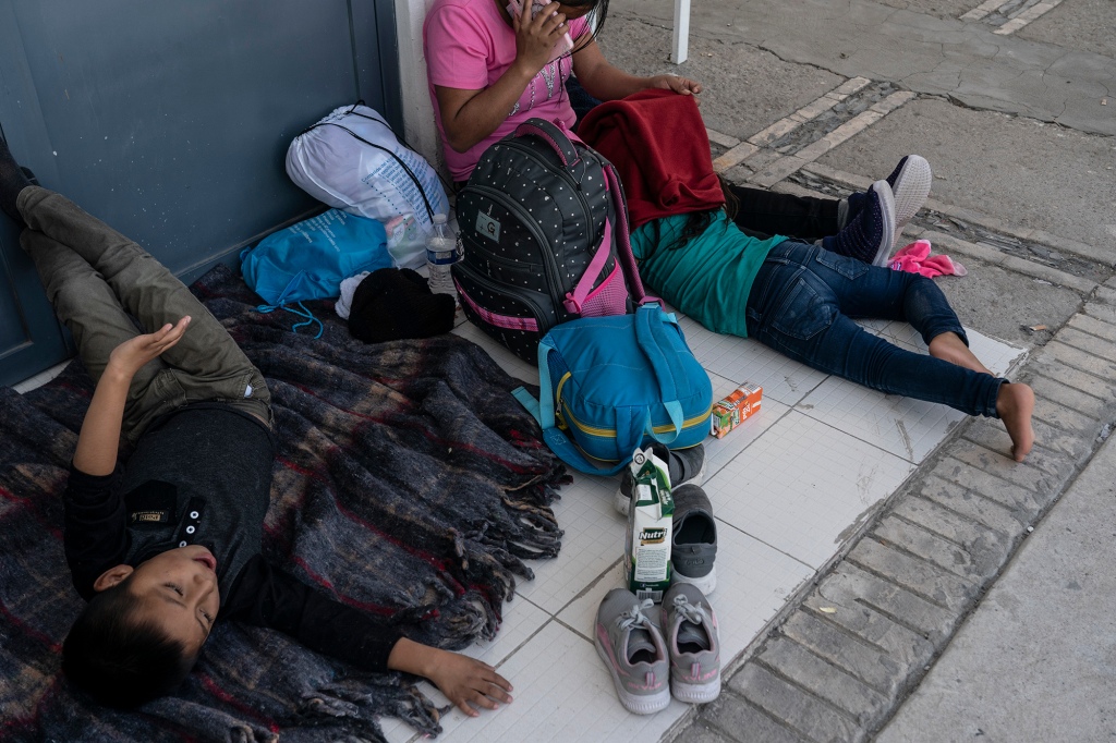 Asylum-seeking migrants mostly from Venezuela rest outside of the Mexican Immigration office.