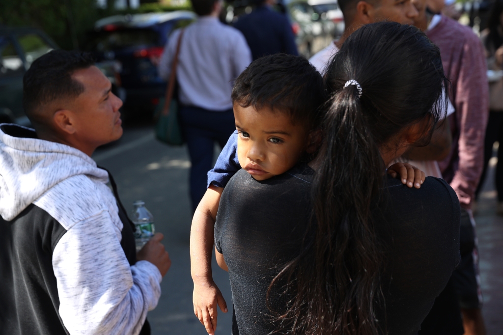 A mother and child spent some time outside the St. Andrew's Parrish House where migrants were being fed lunch with donated food from the community.