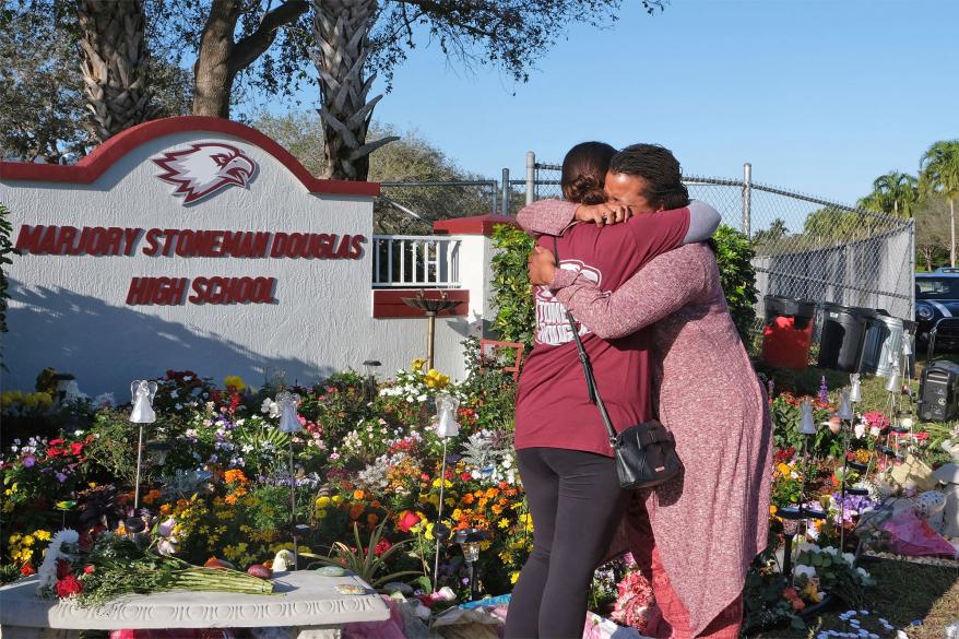 At a makeshift memorial parent s hug in front of Marjory Stoneman Douglas High School in Parkland, Florida on February 14, 2019.