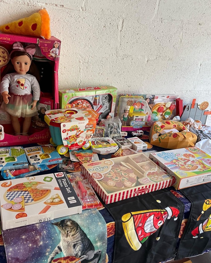 A picture of some of her pizza memorabilia, including a doll wearing a pizza outfit and board games.