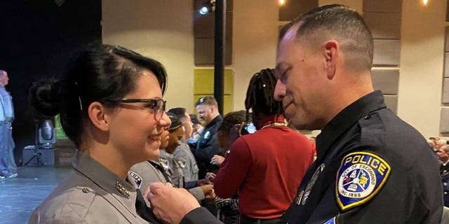 Escondido police Sgt. Valdivia pins the badge on the uniform of El Paso County Deputy Young following her graduation ceremony.