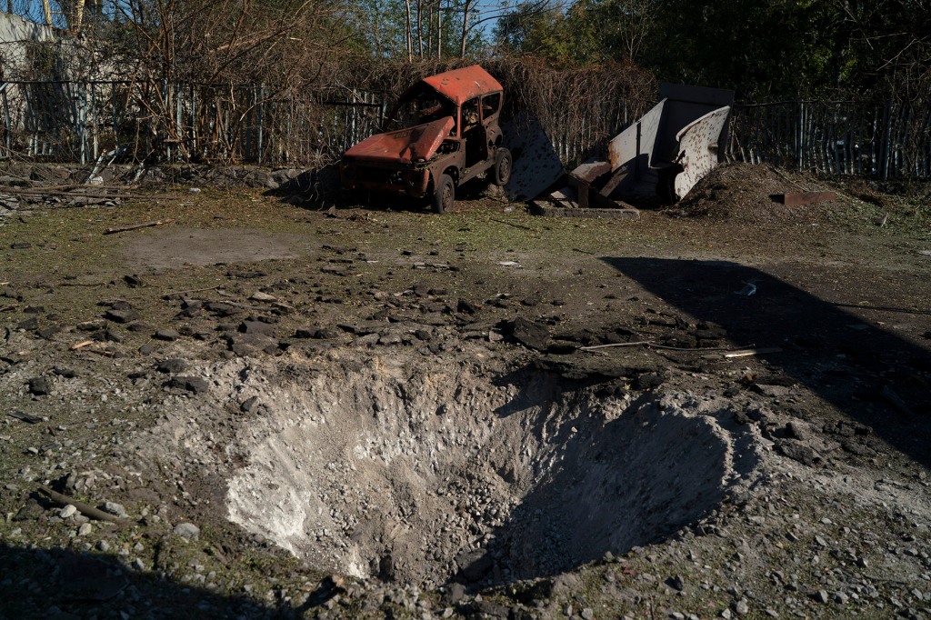 A destroyed car is seen next to a crater created by an explosion on Oct. 15.