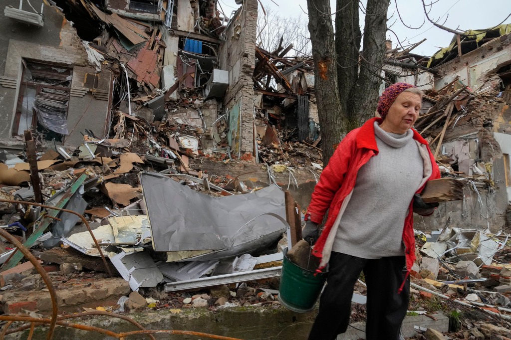 Local resident Nina, 72, carries wooden debris near her house, ruined by the Russian shelling a month ago in central Slavyansk.