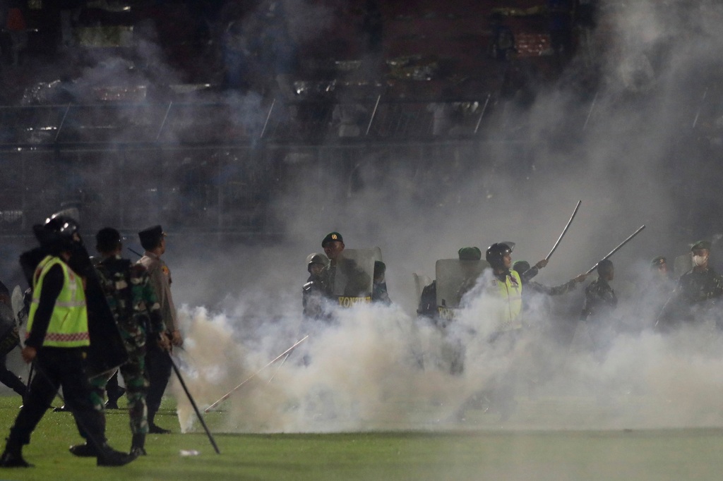 Police officers and soldiers stand amid tear gas smoke just before the stampede.