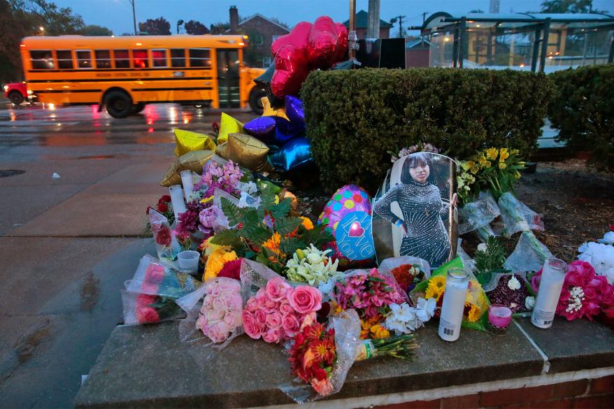 A photo of Alexandria Bell rests at the scene of a growing floral memorial to the victims of a school shooting.