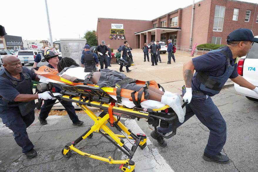 St. Louis firefighters convey a shooting victim to a waiting ambulance.