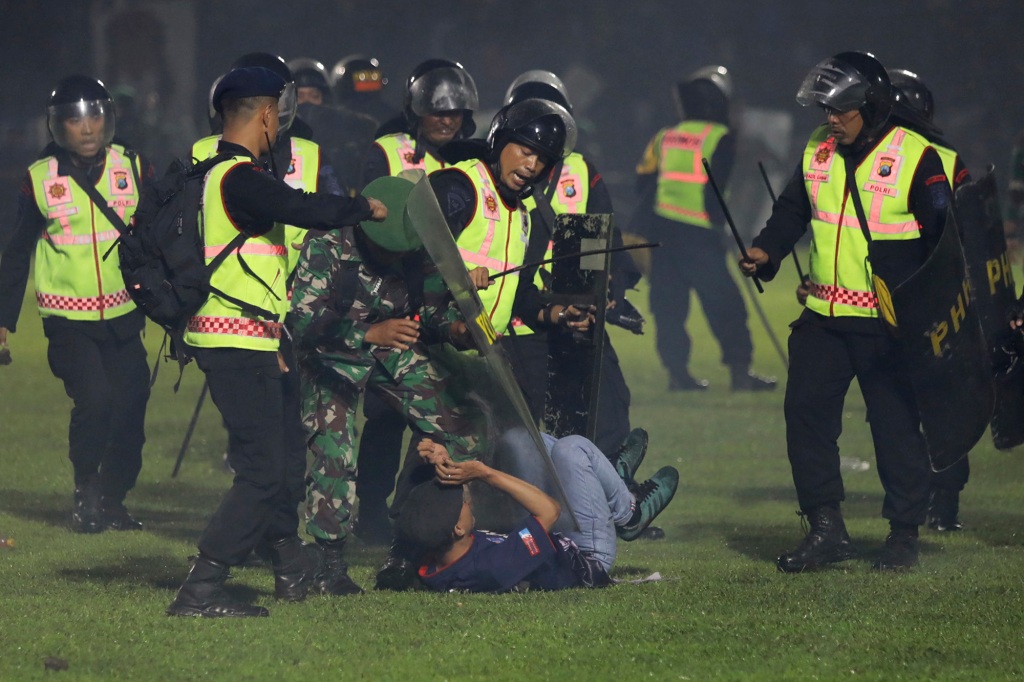 Security officers detain a fan during a clash between supporters of two Indonesian soccer teams at Kanjuruhan Stadium.