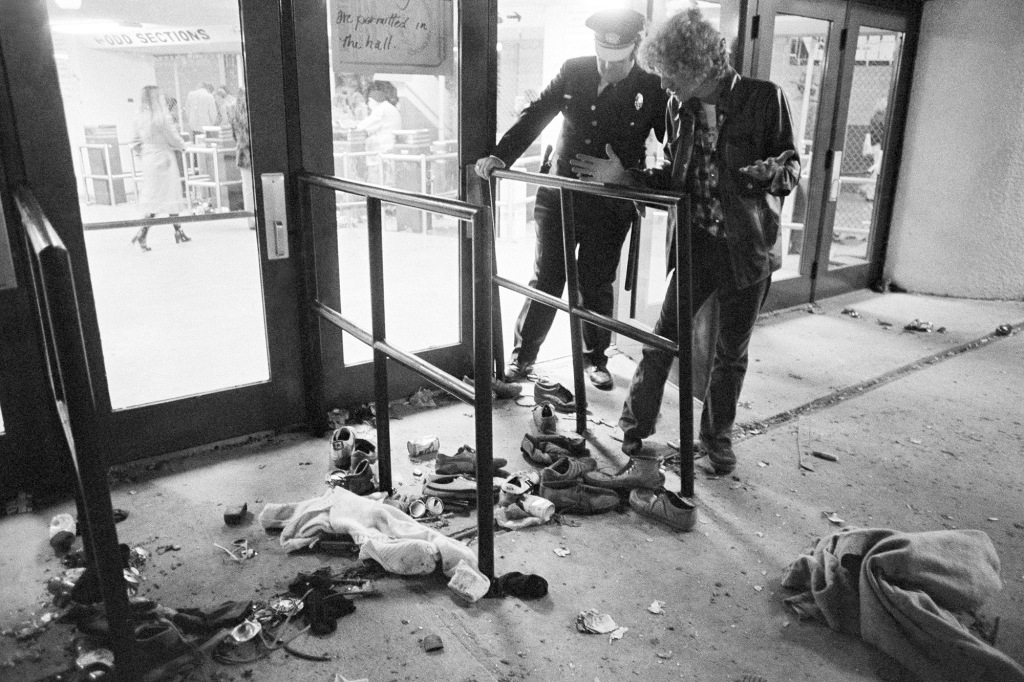 A security guard and an unidentified man look at an area where several people were killed as they were caught in a surging crowd entering Cincinnati's Riverfront Coliseum for a concert by The Who, Dec. 3, 1979.