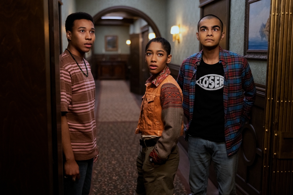 Chris Sumpter as Spencer, Iman Benson as Ilonka, Sauriyan Sapkota as Amesh in "The Midnight Club" standing in a hallway. 