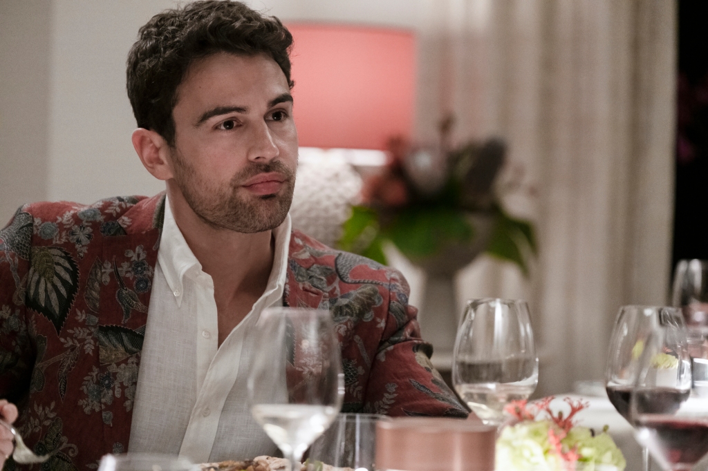 Cameron (Theo James) in "The White Lotus" drinking wine at a table. 