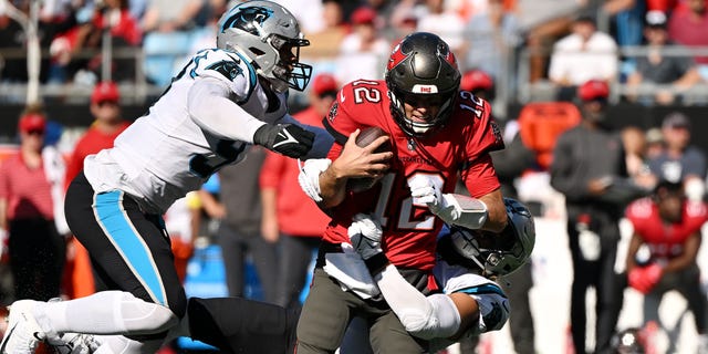 Frankie Luvu of the Carolina Panthers, left, tackles Tom Brady of the Tampa Bay Buccaneers in the third quarter at Bank of America Stadium Oct. 23, 2022, in Charlotte, N.C.