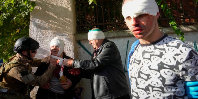 People receive medical treatment at the scene of Russian shelling, in Kyiv, Ukraine, Monday, Oct. 10, 2022. (AP Photo/Efrem Lukatsky)