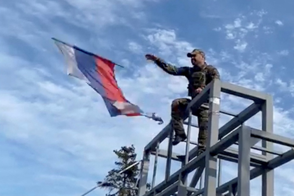 A member of the Ukrainian troop brings down a Donetsk Republic flag hoisted on a monument in Lyman, Ukraine.