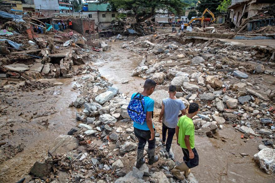 People survey the damage caused by the overflow of the Los Patos stream