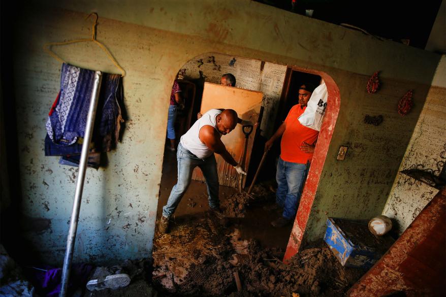 Residents remove mud inside a house that was hit by devastating floods following heavy rain