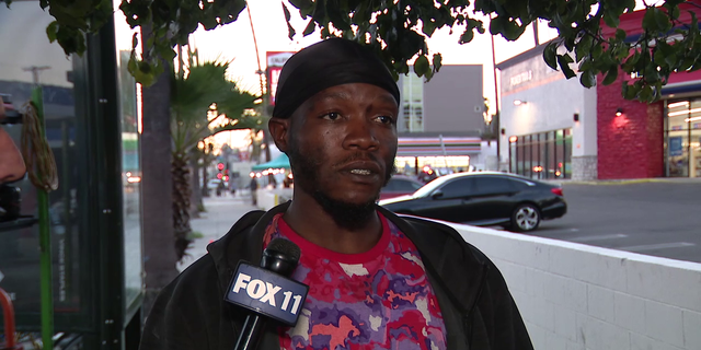 A homeless man who calls himself "Q" speaks to local media asking about a small wooden home he constructed on a sidewalk. 