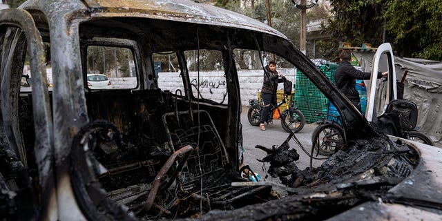 Palestinians look at a damaged car following clashes between Israel army and Palestinians during an Israeli raid in the occupied West Bank city of Nablus, Tuesday, Oct. 25, 2022. The military says Israeli forces have raided a stronghold of an armed group in the West Bank, blowing up an explosives lab and engaging in a firefight. Palestinian health officials say five Palestinians were killed and 20 were wounded. The target of the raid was a group calling itself the Lions' Den, accused by Israel of having killed a soldier and attempting several attacks. 