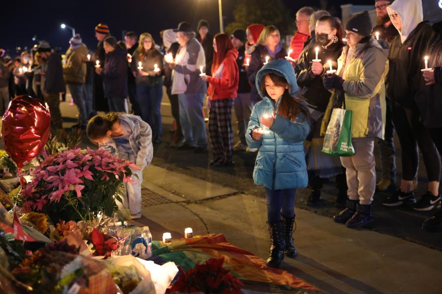 A little girl is spotted with a candle near a makeshift memorial for the Club Q nightclub victims on Nov. 20, 2022 in Colorado Springs, Colo.