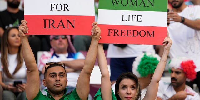 Iranian soccer fans hold up signs reading Woman Life Freedom and Freedom For Iran, prior to the World Cup group B soccer match between England and Iran at the Khalifa International Stadium in Doha, Qatar, Monday, Nov. 21, 2022.