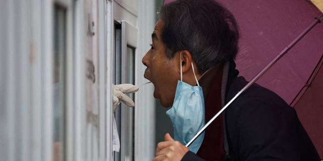 A man has his swab sample taken at a testing booth, in Beijing, China on Nov. 11, 2022.