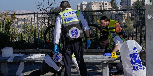 Members of Zaka Rescue and Recovery team clean blood from the scene of an explosion at a bus stop in Jerusalem, Wednesday, Nov. 23, 2022.