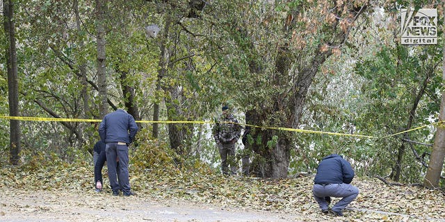 Investigators are seen searching parking lot area behind the  house in Moscow, Idaho Monday, November 21, 2022, where four people were slain on November 13.