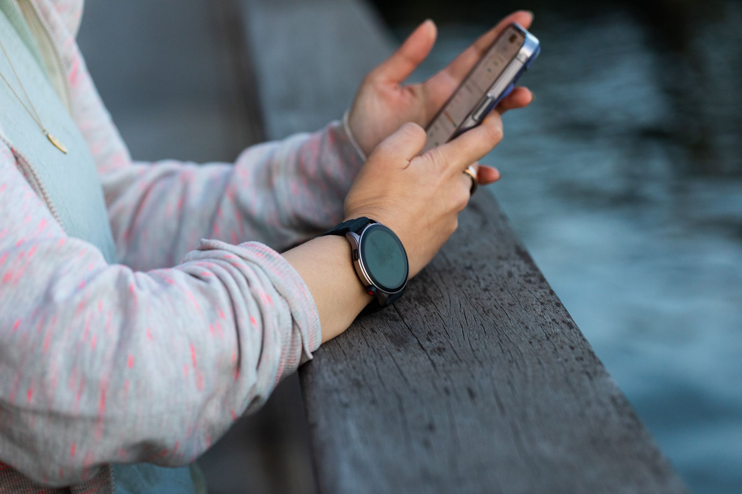 Woman wearing Amazfit GTR 4 at a pier while looking at her phone