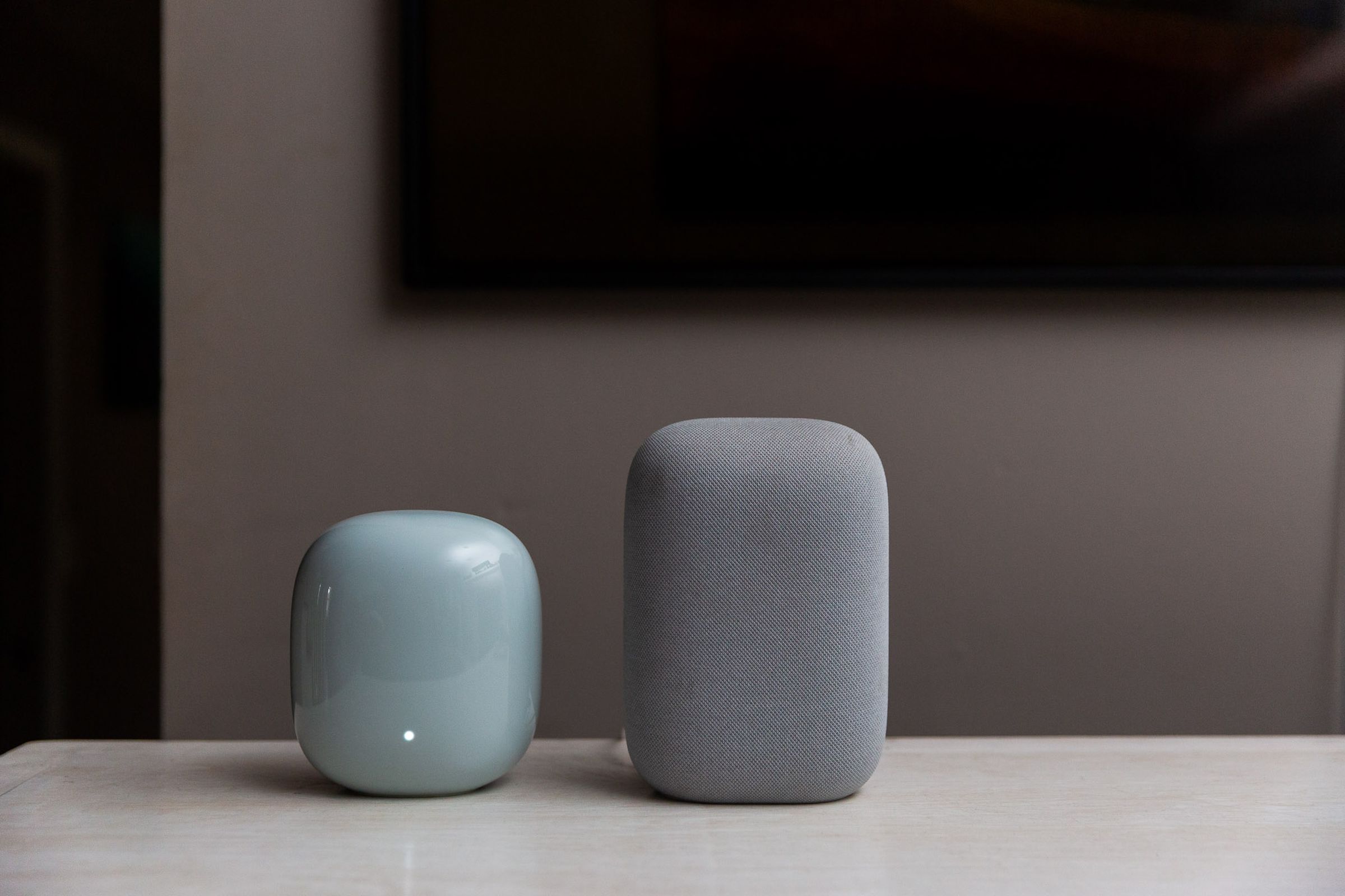 A Nest Wifi Pro router on a table next to a Nest Audio speaker.