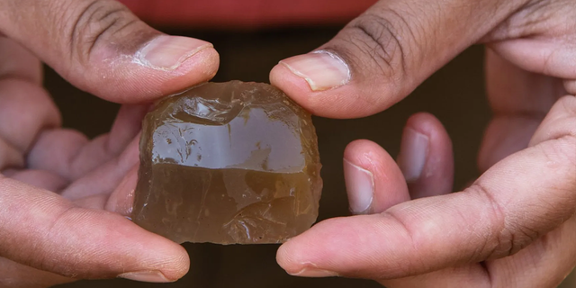 An archeologist holds a French musket flint found from one of the Continental burials.