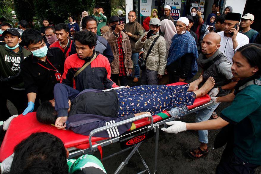 People evacuate a wounded woman on a stretcher following a landslide triggered by the earthquake in Cianjur on Nov. 21, 2022.