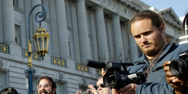 David DePape, right, records the nude wedding of Gypsy Taub outside City Hall on Dec. 19, 2013, in San Francisco. DePape is accused of breaking into House Speaker Nancy Pelosi's California home and severely beating her husband with a hammer. DePape was known in Berkeley, Calif., as a pro-nudity activist who had picketed naked at protests against local ordinances requiring people to be clothed in public.