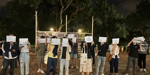 Protesters hold up blank pieces of paper during a commemoration for victims of a recent Urumqi deadly fire in Hong Kong, Monday, Nov. 28, 2022.