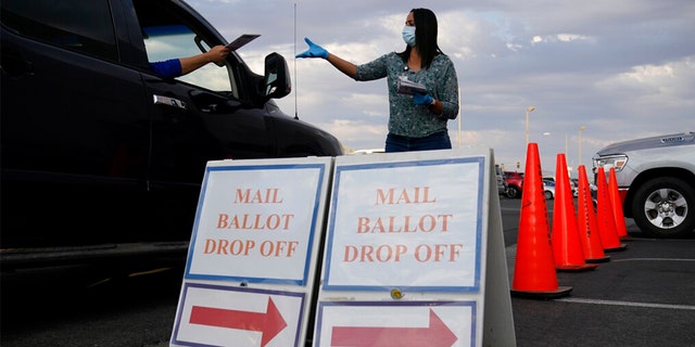 FILE: A county worker collects mail-in ballots in a drive-thru mail-in ballot drop off area at the Clark County Election Department in Las Vegas.