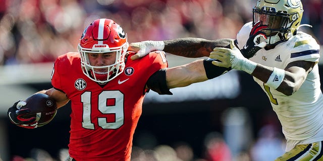 Georgia tight end Brock Bowers (19) fends off Georgia Tech defensive back Zamari Walton (7) as he runs after a catch during the first half of an NCAA college football game Saturday, Nov. 26, 2022 in Athens, Ga. Bowers was called for a face masking penalty.