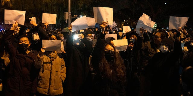 Protesters hold up blank papers and chant slogans as they march in protest in Beijing, Sunday, Nov. 27, 2022. 