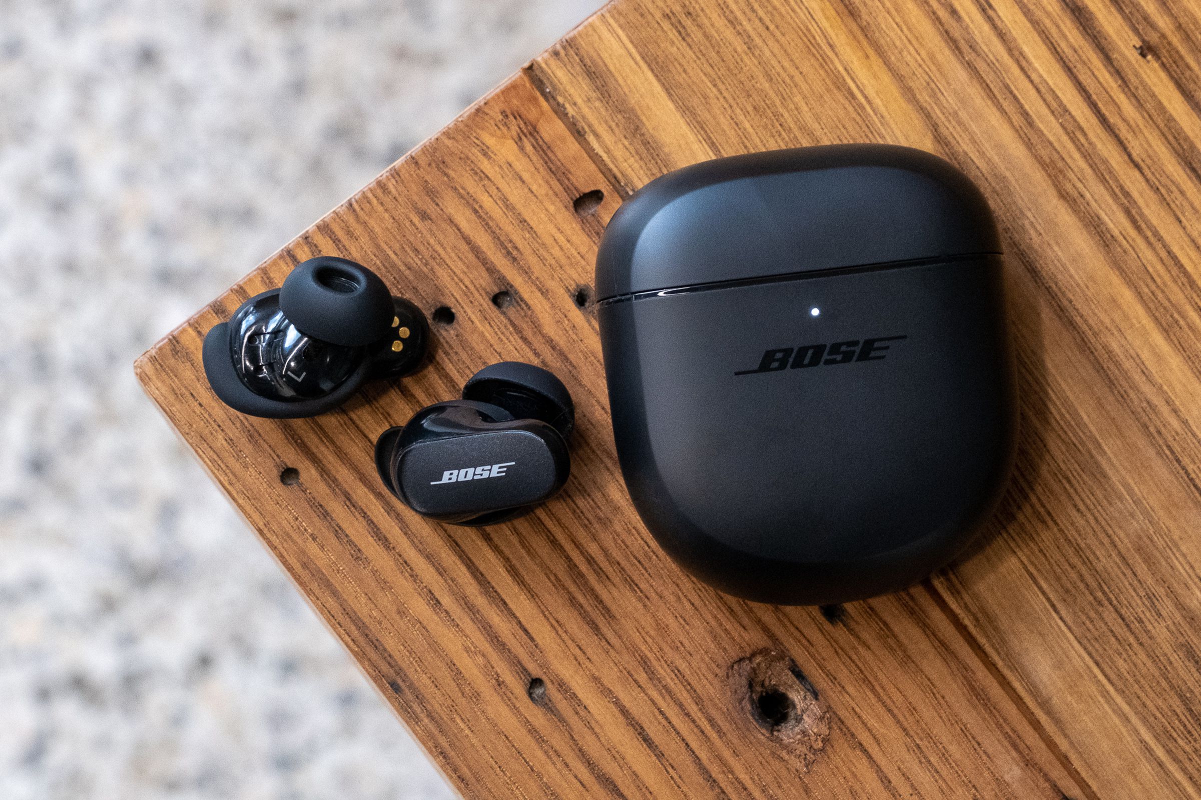 An overhead image of the Bose QuietComfort Earbuds II on a wood table.