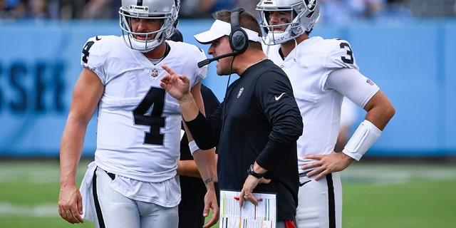 Las Vegas Raiders head coach Josh McDaniels talks with quarterback Derek Carr (4) in the second half of an NFL football game against the Tennessee Titans Sunday, Sept. 25, 2022, in Nashville, Tenn. 