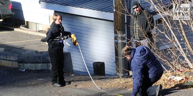 A forensics team returned to the street in front of the crime scene to measure tire marks.