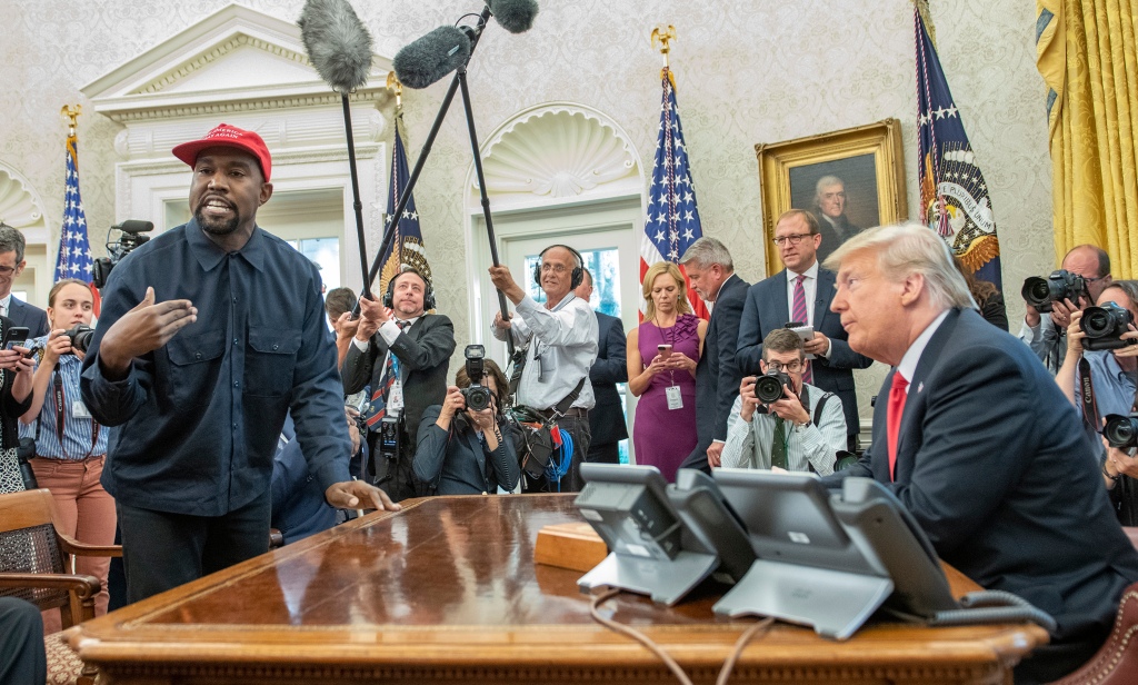 Kanye West stands as he talks with real estate developer and US President Donald Trump in the White House's Oval Office in Washington D.C. on Oct. 11, 2018. 