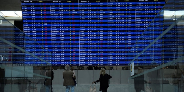 This photograph taken on September 16, 2022, shows travellers looking at the departure information panel of the Terminal 2 of the Roissy-Charles de Gaulle airport. 