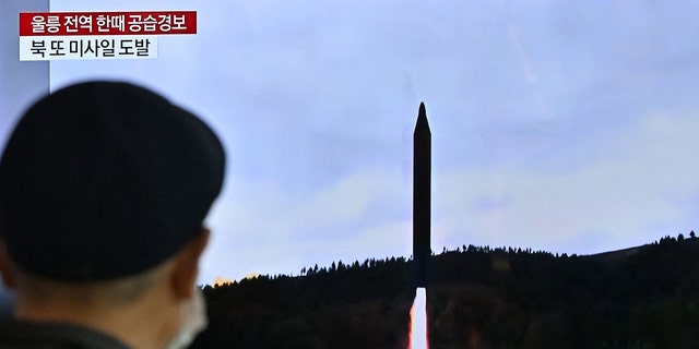 A man watches a television screen showing a news broadcast with file footage of a North Korean missile test, at a railway station in Seoul on November 2, 2022. 