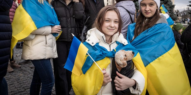 People drink sparkling wine, waves flags and sing songs as they celebrate the liberation of part of the city of Kherson in Independence Square on Nov. 12, 2022, in Kyiv, Ukraine. 