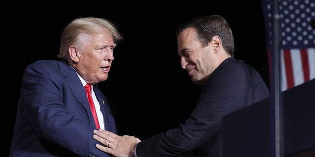 MINDEN, NEVADA - OCTOBER 08: Nevada republican U.S. Senate candidate Adam Laxalt greets former U.S. President Donald Trump on stage during a campaign rally at Minden-Tahoe Airport on October 08, 2022 in Minden, Nevada. 