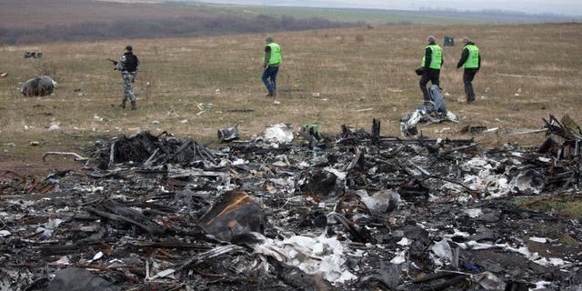 Dutch investigators accompanied by pro-Russian armed rebels arrive near parts of the Malaysia Airlines Flight MH17 at the crash site near the Grabove village in eastern Ukraine on November 11 2014, hoping to recover debris from the Malaysia Airlines plane which crashed in July, killing 298 people, in remote rebel-held territory east of Donetsk. 