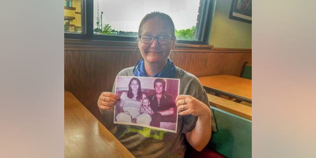 Holly is pictured here holding a photo of her parents Dean and Tina Clouse.