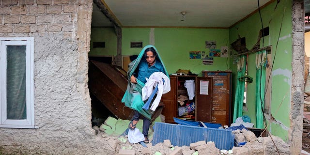 A man collects clothings from his damaged house following an earthquake in Cianjur, West Java, Indonesia Tuesday, Nov. 22, 2022.