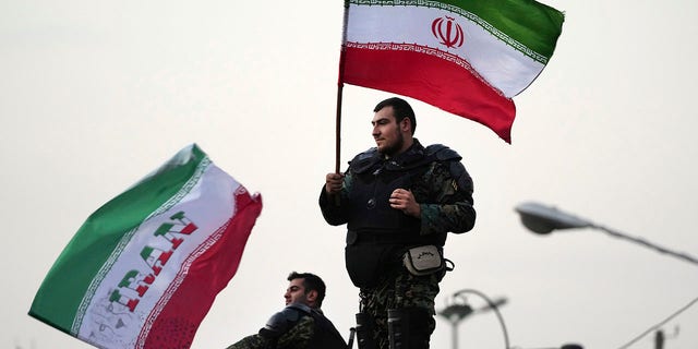 Two anti-riot police officers wave the Iranian flags during a street celebration after Iran defeated Wales in Qatar's World Cup at Sadeghieh Square in Tehran, Iran.